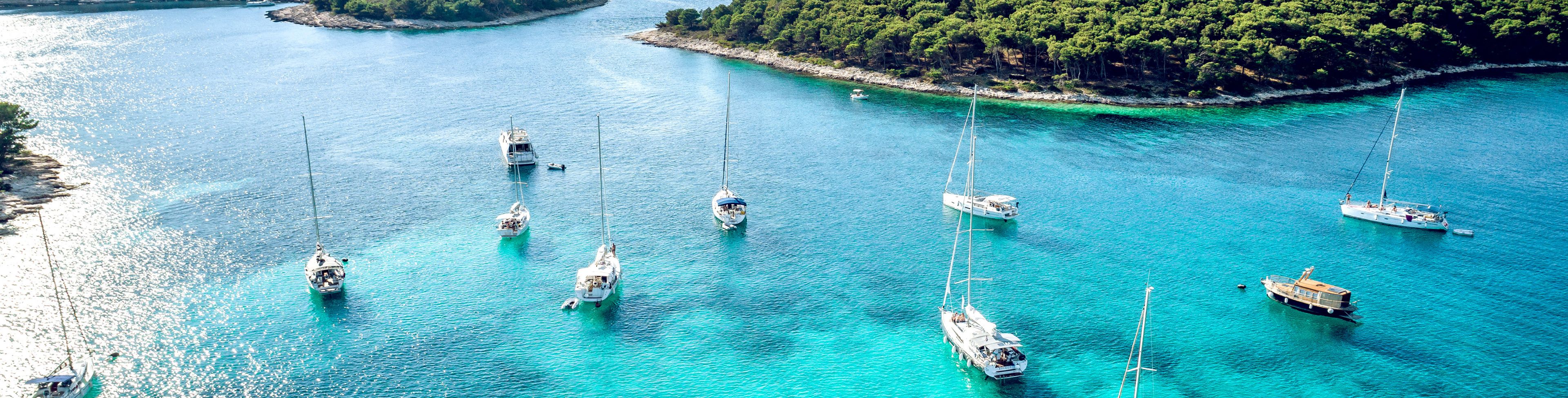 Many different boats and yachts anchored near shore.