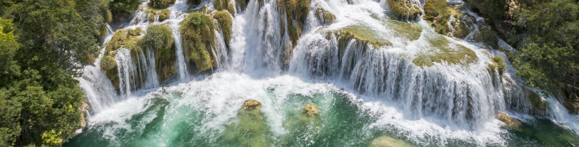 Aerial view of a cluster of waterfalls surrounded by a forest. 