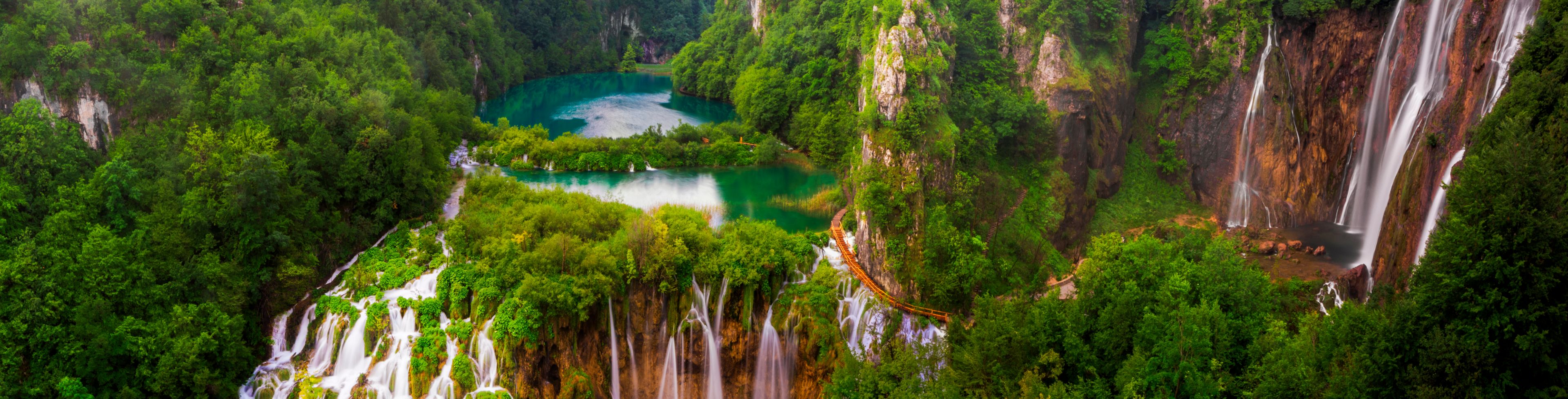 A birds-eye view of a several trees, waterfalls, and nature's swimming pools.