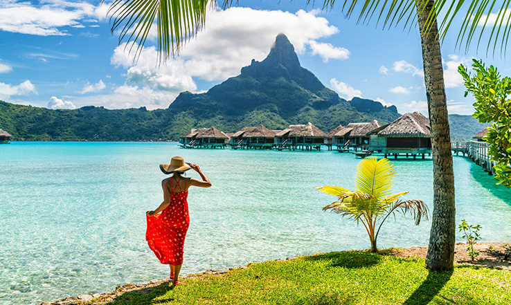 Woman looking out at the beach and mountain in the distance. 