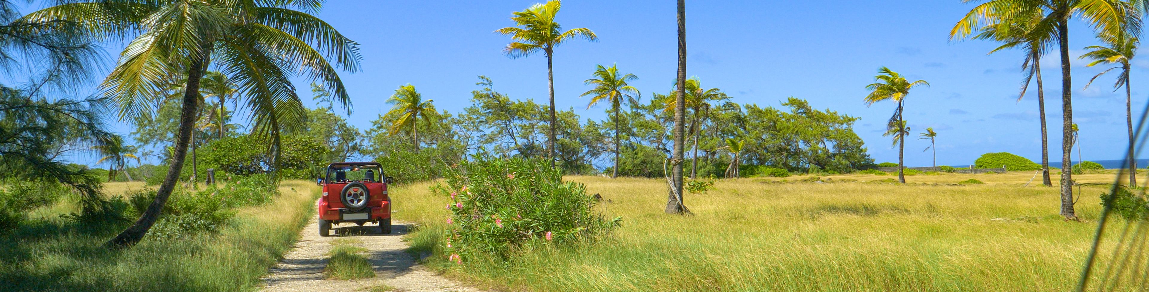 Red jeep driving down a dirt road.