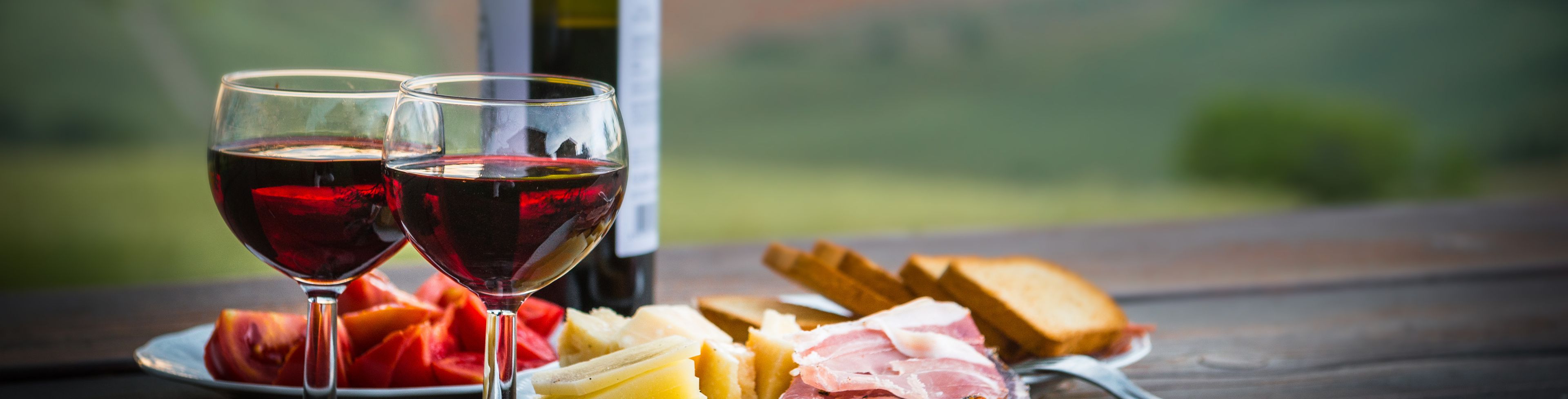 Wine bottles and glasses along with plates of fruit, meat, and cheese ready to enjoy.
