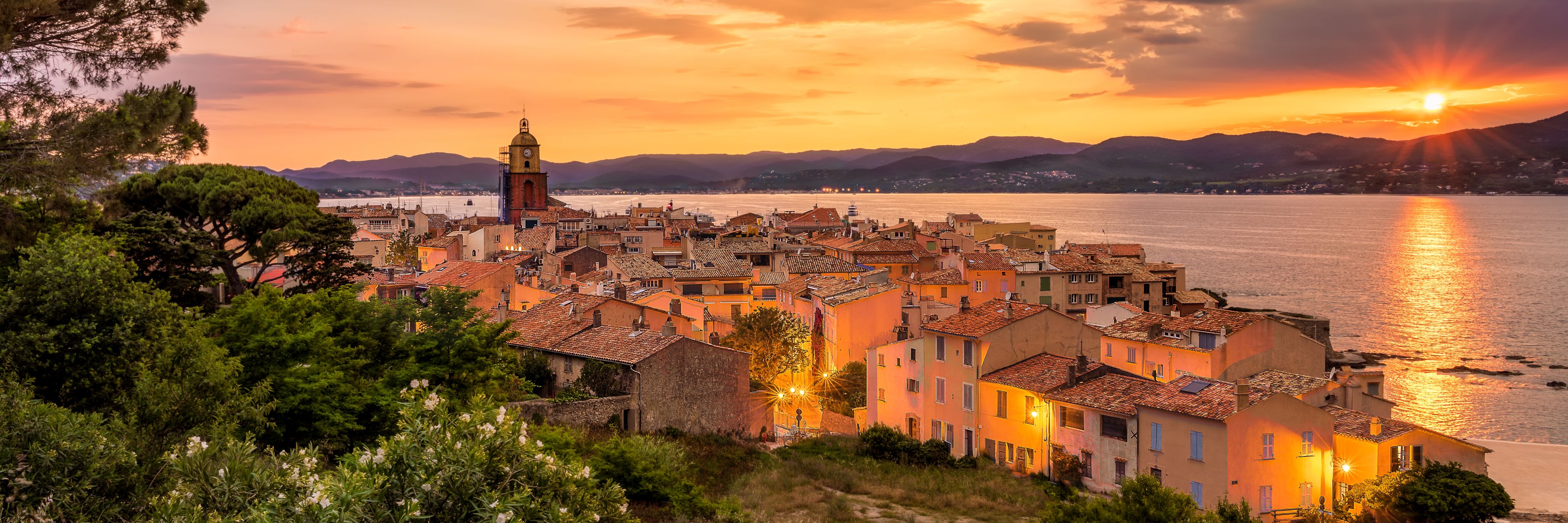 City next to the water with the sun setting.