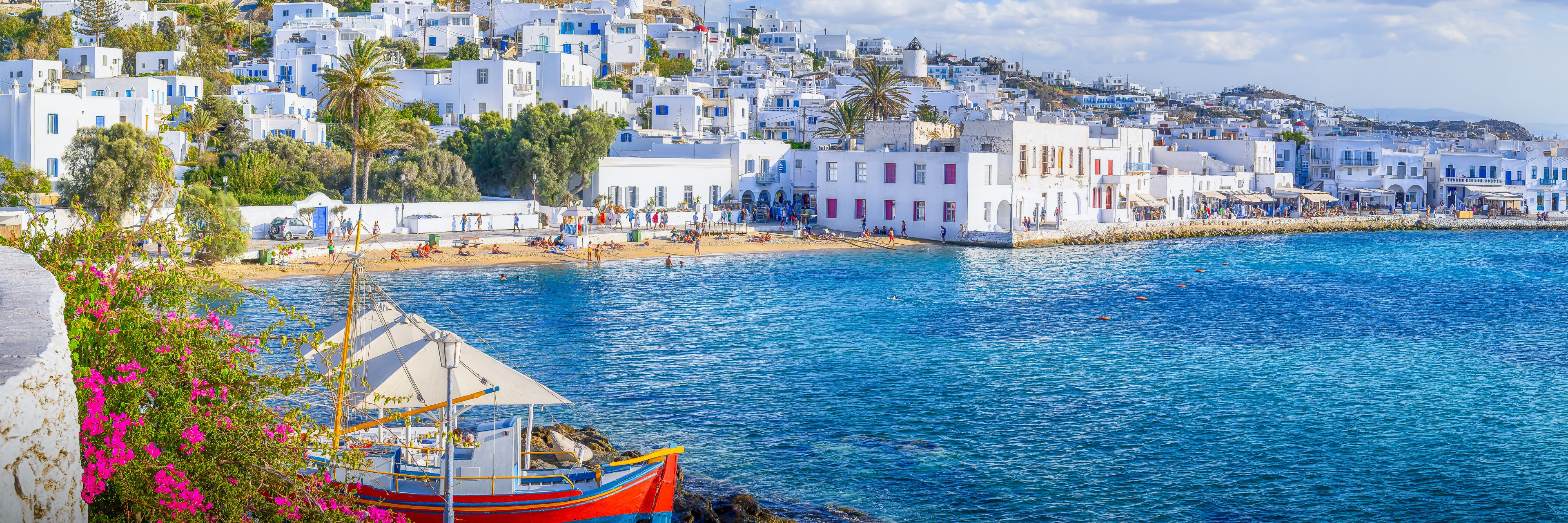 View of a city on a slight hillside and boats, overlooking the ocean.