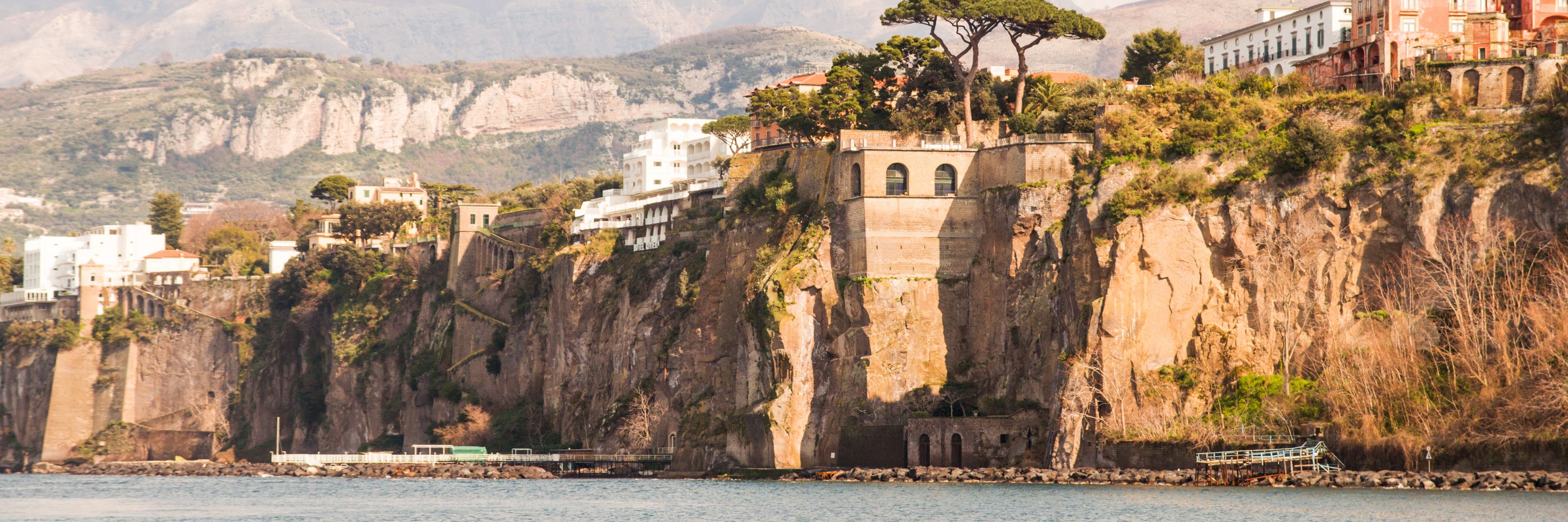 Buildings on and built into the cliffside with the ocean below.
