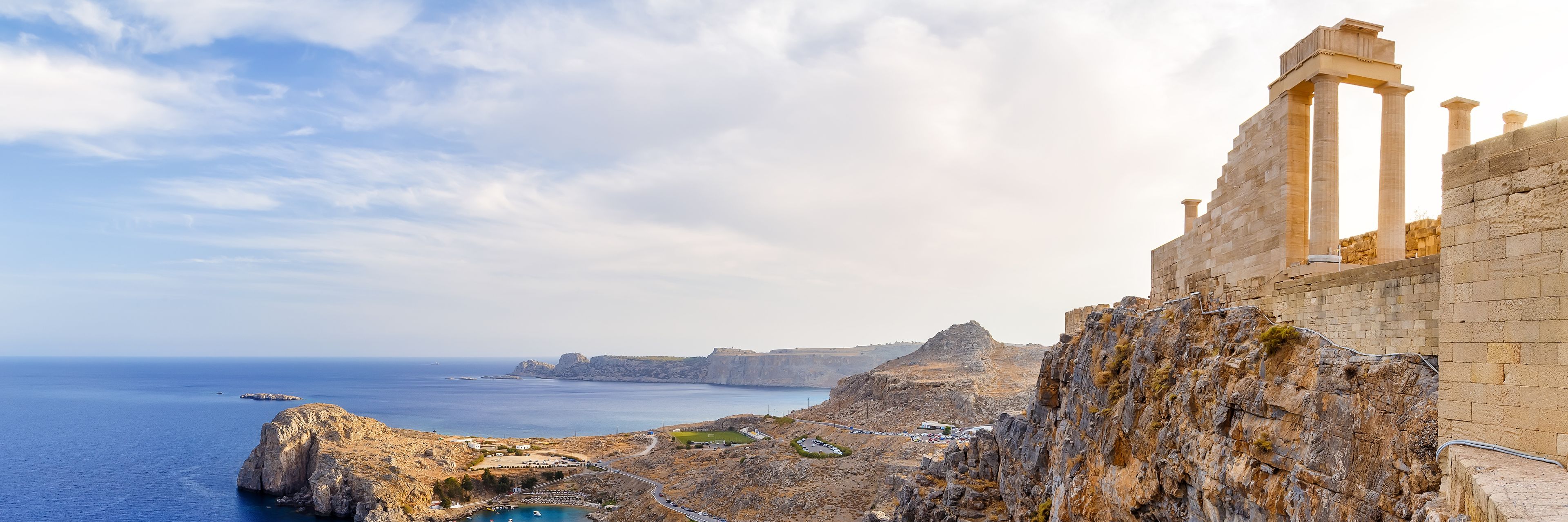 Ruins on top of a mountain top overlooking the land and the ocean.