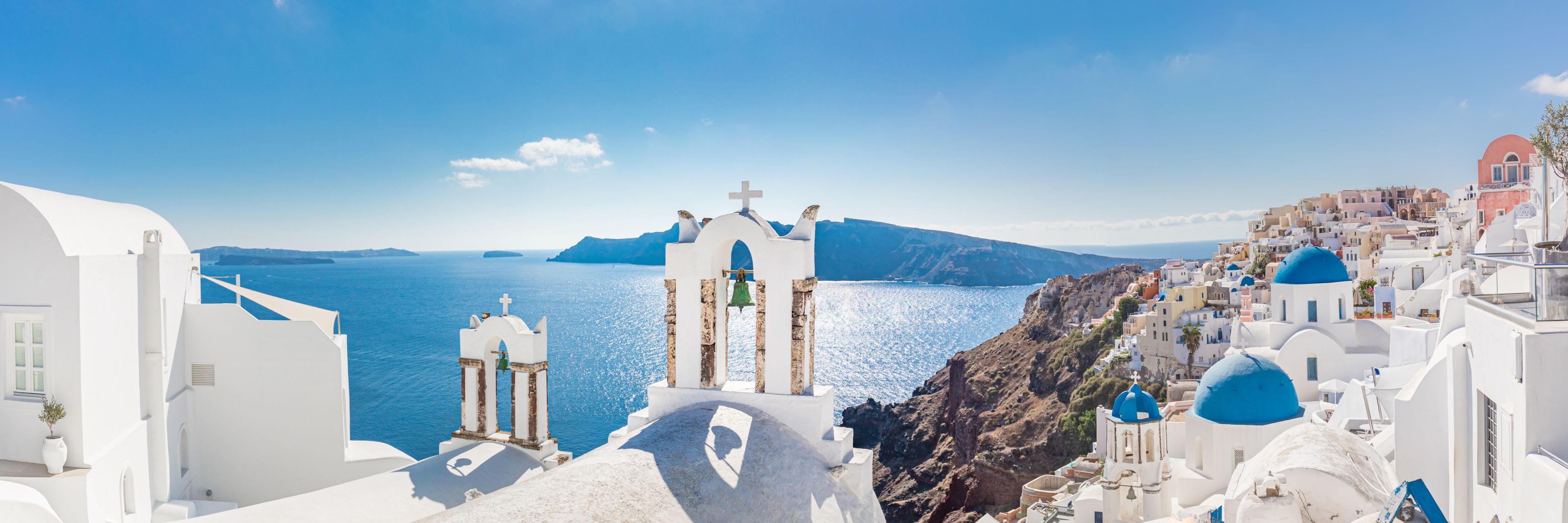 City buildings on top of a mountaintop and cliffside, overlooking the sea.