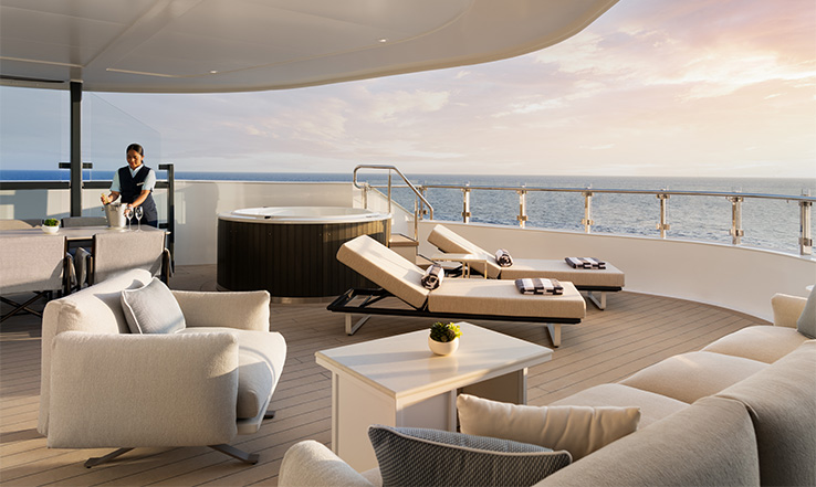 Lounge chairs and couches on a deck overlooking ocean.