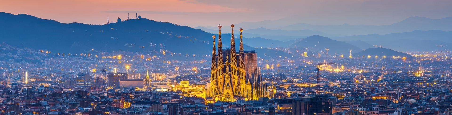 The Sagrada Familia is illuminated, standing out from the rest of the city.