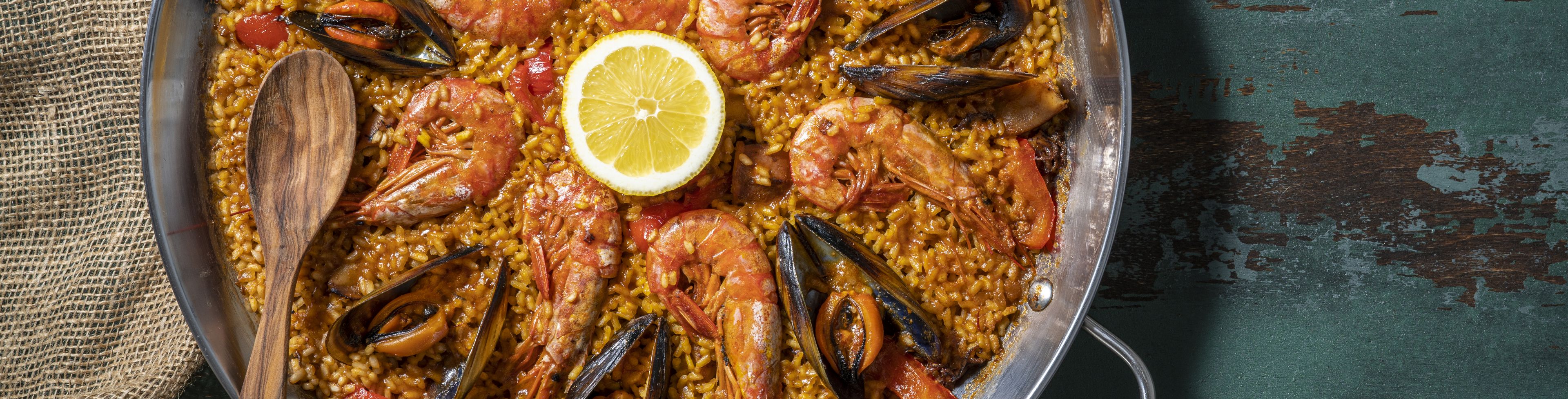 A large platter of paella sits centered. 