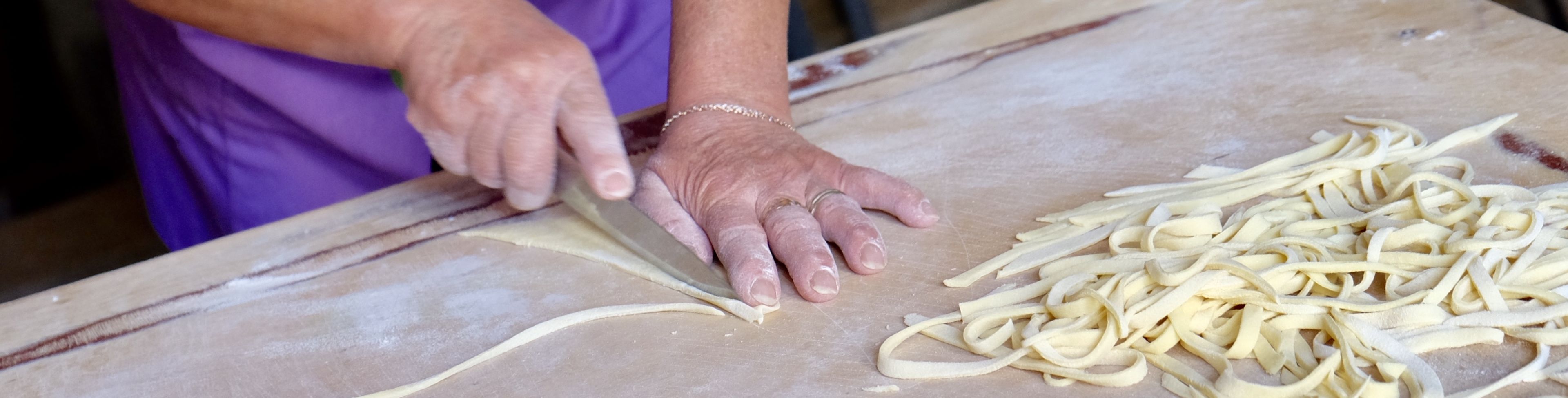 Person cutting dough on a cooking table.