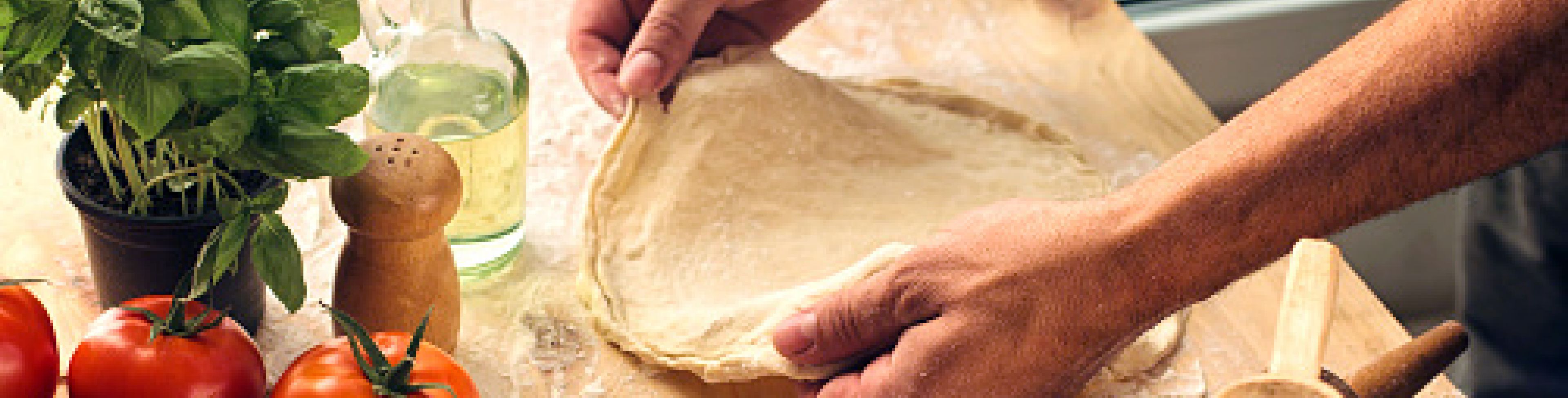 Someone making dough, surrounded by fresh cooking ingredients. 