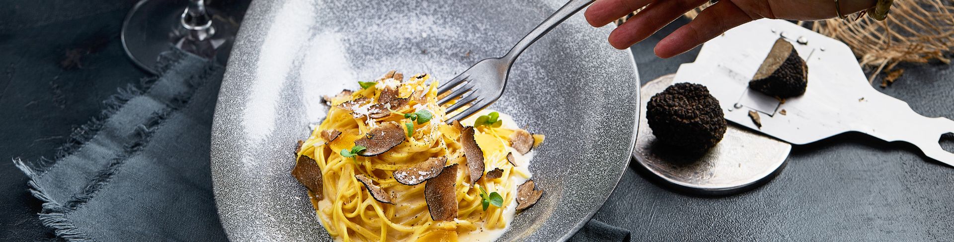 A person using a fork to eat their noodle dish out of a bowl.