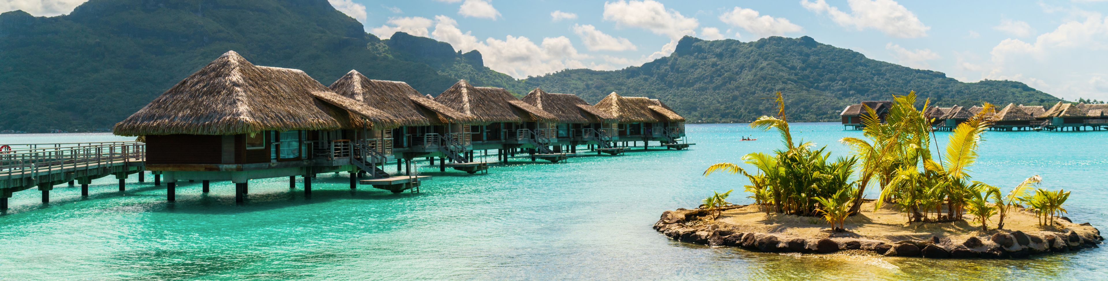 Person paddle boarding near the Bora Bora huts.