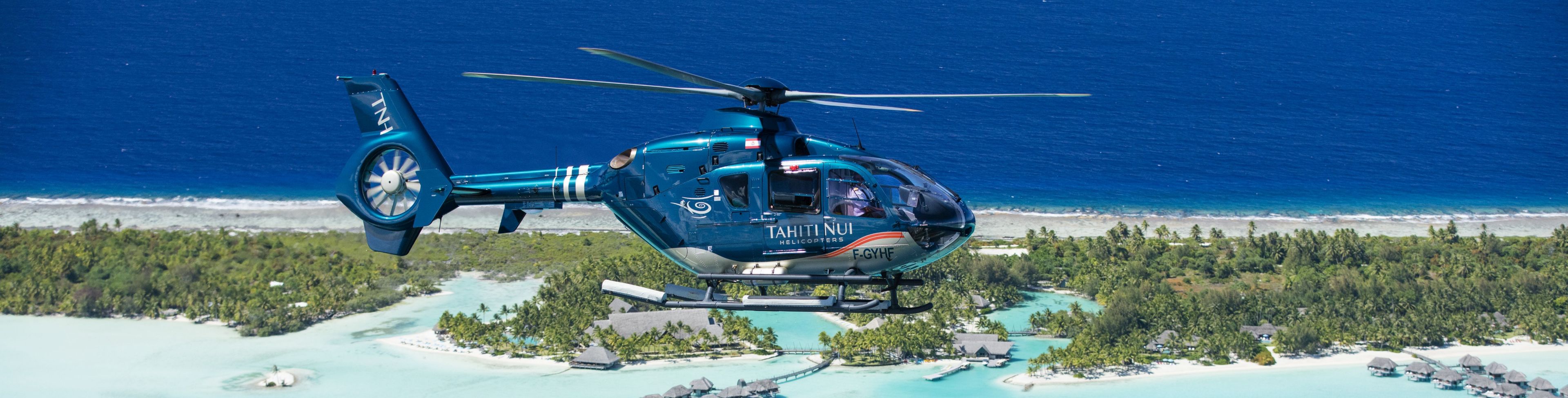 Helicopter flying over water and around the island. 