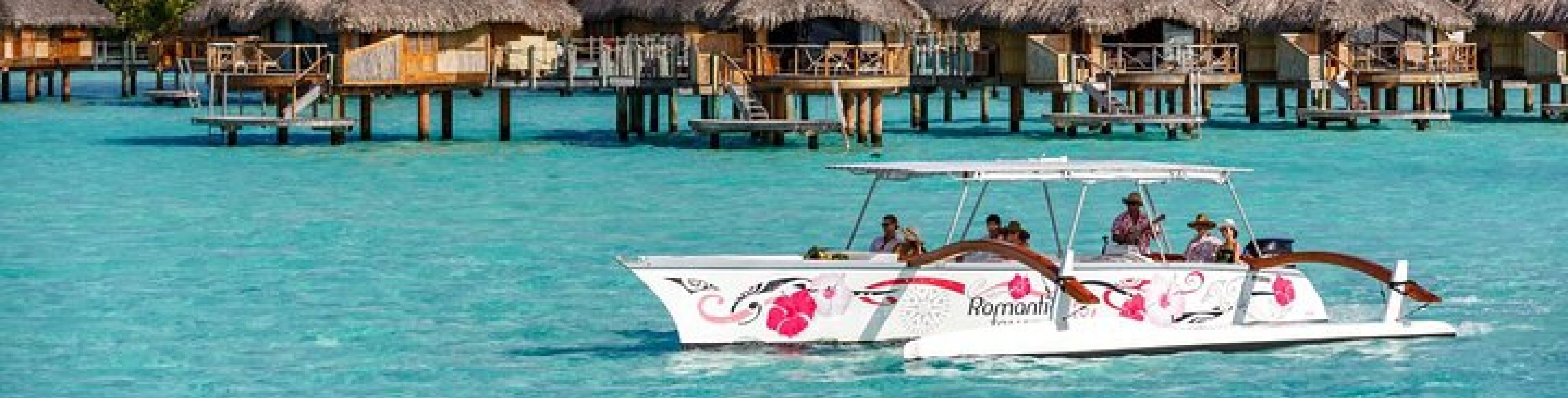People on a boat going by the Bora Bora huts. 
