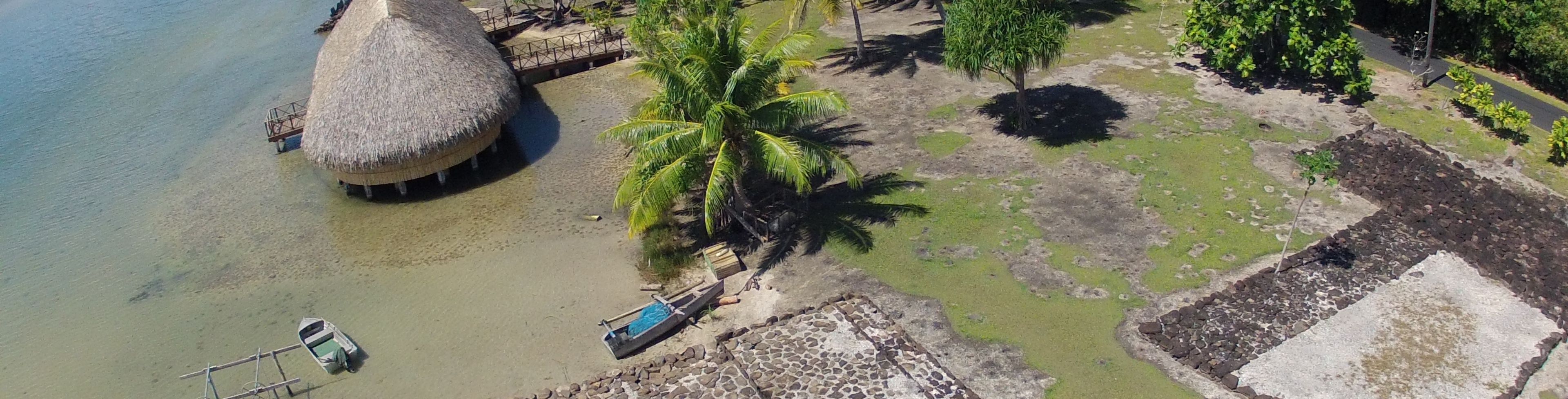 Sky view of water and grounds near a hut.