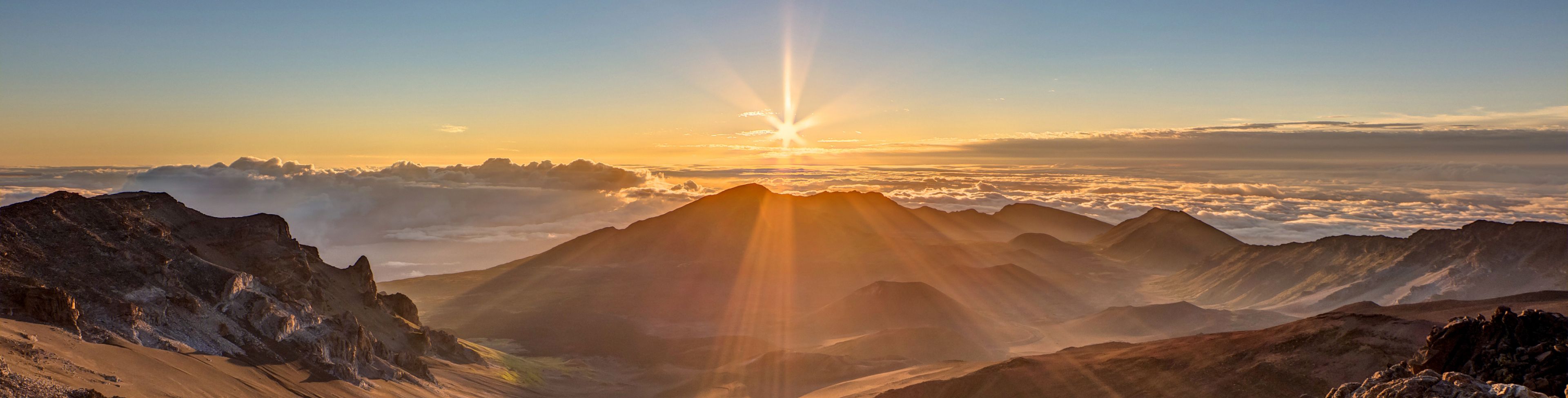 Sun setting over sandy mountains and valleys.